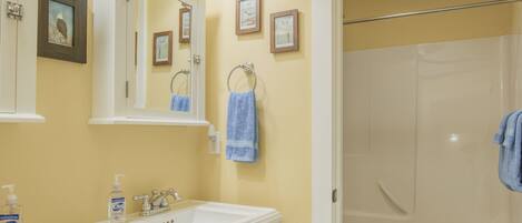 A bathroom with two sinks, a mirror, a toilet, and a shower.