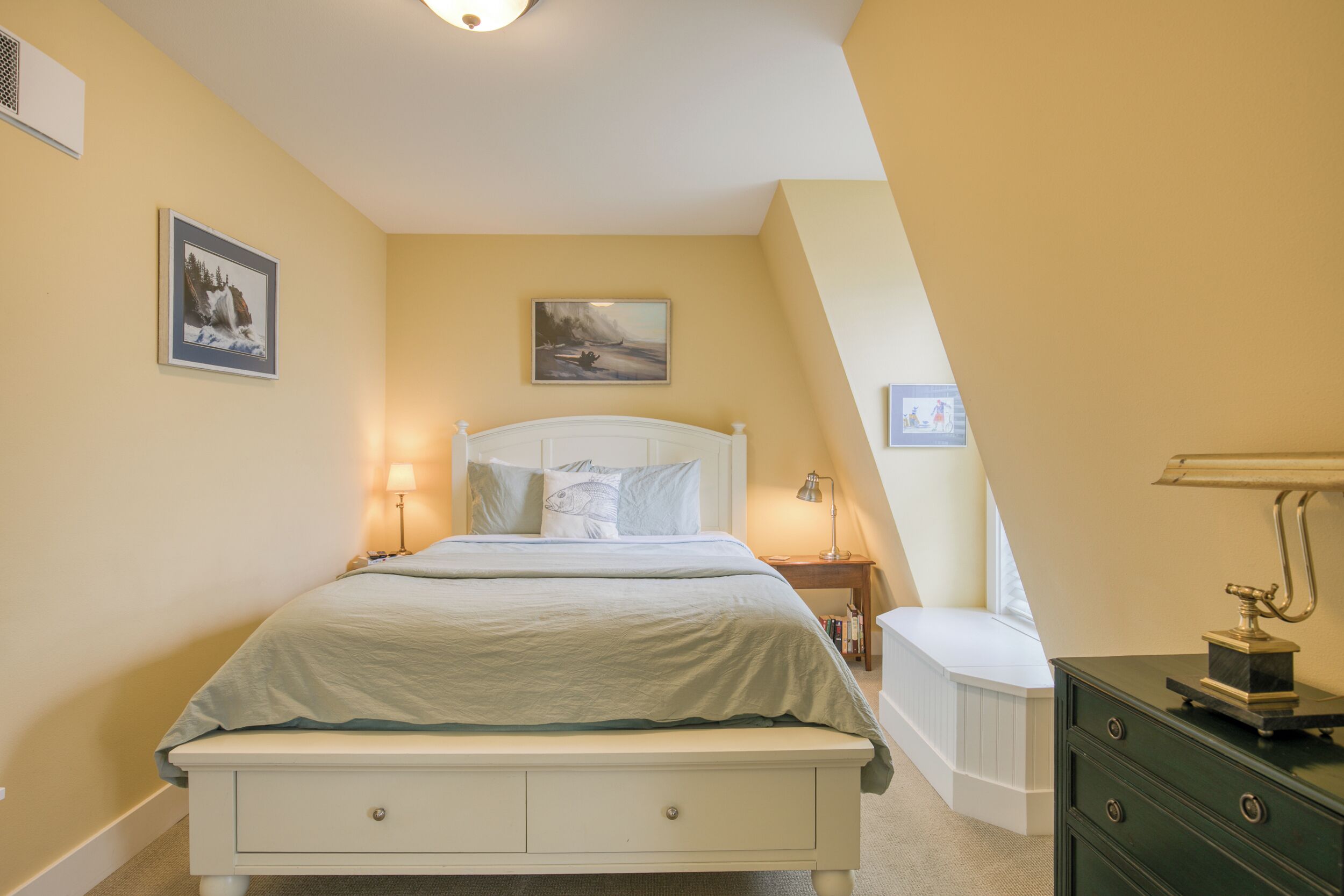 A bedroom with a bed, bedside tables, and a dresser.