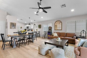 A modern living room with a sofa, coffee table, and dining area with chairs and a table.