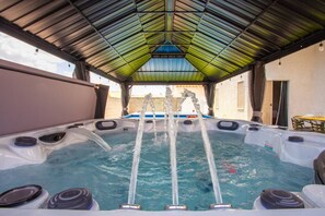 A hot tub with jets, surrounded by a covered area with a metal roof.