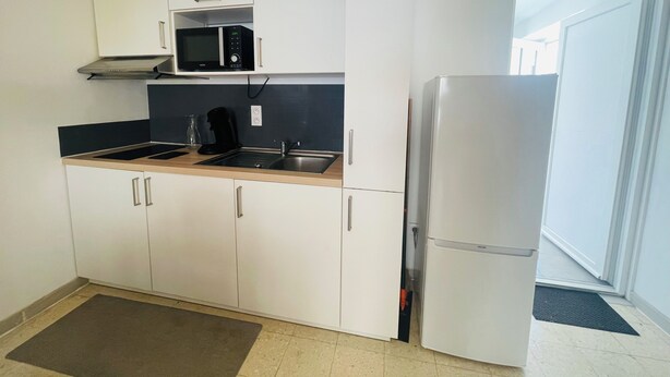 A modern kitchen with white cabinets, a microwave, a sink, and a refrigerator.