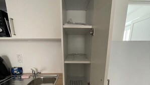 A kitchen with a stainless steel sink, a refrigerator, and a built-in pantry with multiple shelves.