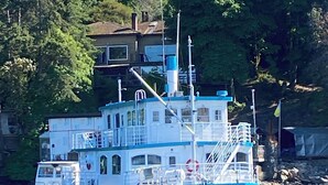 A boat docked near a house with a dock, surrounded by trees.