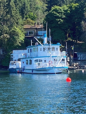 A boat docked near a house with a dock, surrounded by trees.