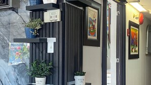 A hallway with a marble wall, black shelving units, and potted plants.