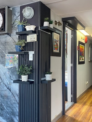 Stylish hallway with a marble accent wall, potted plants, and a mounted radio.