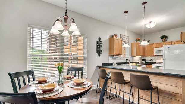 A modern kitchen with wooden cabinets, a central island, and pendant lighting.