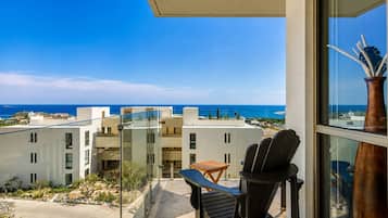 A balcony with a view of the sea, a chair, and a table.