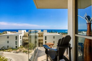A balcony with a view of the sea, a chair, and a table.