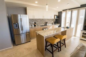 A modern kitchen with a central island, stainless steel appliances, and a bar stool seating area.