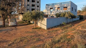 A modern building with a flat roof and large windows, surrounded by dry grass and a few trees.
