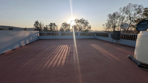 A rooftop terrace with a clear view of the sunset, a satellite dish, and a water tank.