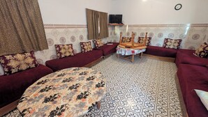 A living room with a sofa set, a round coffee table, and patterned floor tiles.