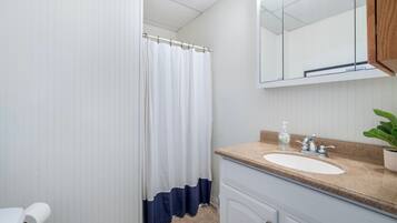 A bathroom with a white sink, a mirror, and a shower curtain.