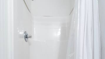 A white shower stall with a showerhead and a drain.