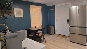 Una cocina compacta con comedor, un refrigerador y un pequeño cubo de basura.