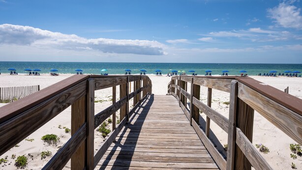 A wooden boardwalk leading to a beach with blue umbrellas. - Skip the packed high-rises!•
Steps to Beach • Family Ready • 
Gulf View 2BR-2BA (Orange Beach)