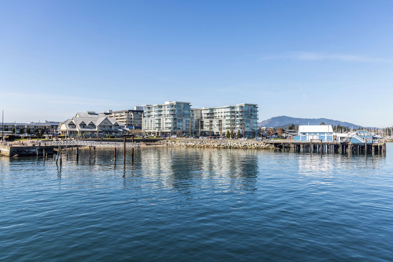 Un hôtel situé au bord de l’eau, doté d’une architecture moderne, de plusieurs étages et d’une façade en verre remarquable.