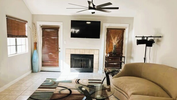 A living room with a beige sofa, a glass coffee table, a fireplace, and a mounted TV. - Style & Convenience Near PHX Ask for LongTerm Rate (Tempe)