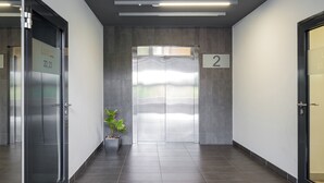 A modern elevator with a number 2 sign, a potted plant, and a clean, tiled floor in a hallway.