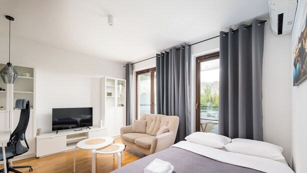 A modern hotel room with a bed, a TV, a chair, and a desk.