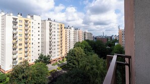 A residential area with multi-story apartment buildings, a clear sky, and lush greenery.
