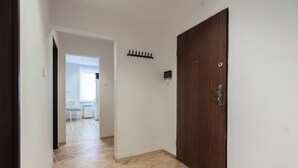 A hallway with a wooden door, a coat rack, and a chair in the background.