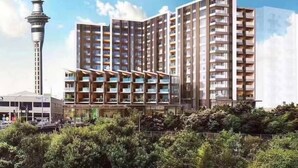 A modern high-rise building with multiple balconies, a prominent tower, and lush greenery in the foreground. - Heart of AKL Modern Studio PoolGymSauna (Auckland)