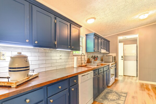 Kitchen features a dishwasher, microwave, and stove, with a tiled backsplash and wooden floor.