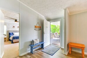 Ein Zimmer mit einem Bett, einer Sitzbank, einer Tür zu einem Außenbereich und einem kleinen Tisch.