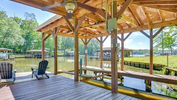 Une terrasse en bois avec un belvédère, des chaises et une vue sur un lac.