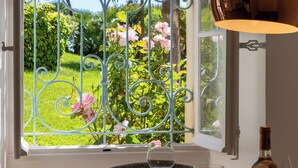A window with ornate metal bars and a view of a garden with pink flowers. - Garden-Level Apartment in Bourgeois Residence – Near Croisette & Beaches (Cannes)