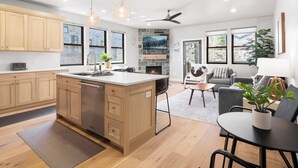 A modern kitchen with wooden cabinets, a central island, and pendant lighting. - Mayflower Lakeside 103 | Mountain View | Balcony | Full Kitchen | Private Bedrooms | Fireplace (Heber City)
