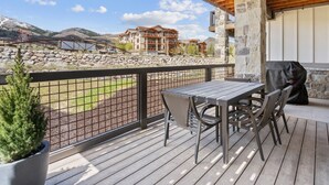 A wooden deck with a table and chairs, overlooking a mountainous landscape and a body of water. - Mayflower Lakeside 103 | Mountain View | Balcony | Full Kitchen | Private Bedrooms | Fireplace (Heber City)