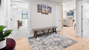 A modern interior with a bench, a patterned rug, and artwork on the wall. - Mayflower Lakeside 103 | Mountain View | Balcony | Full Kitchen | Private Bedrooms | Fireplace (Heber City)