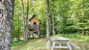 A wooden cabin with a balcony, surrounded by a forest.