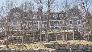 A large, multi-story house with a stone facade and multiple windows.
