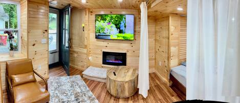 A cozy cabin interior with a wooden interior, a fireplace, a television, and a comfortable seating area.