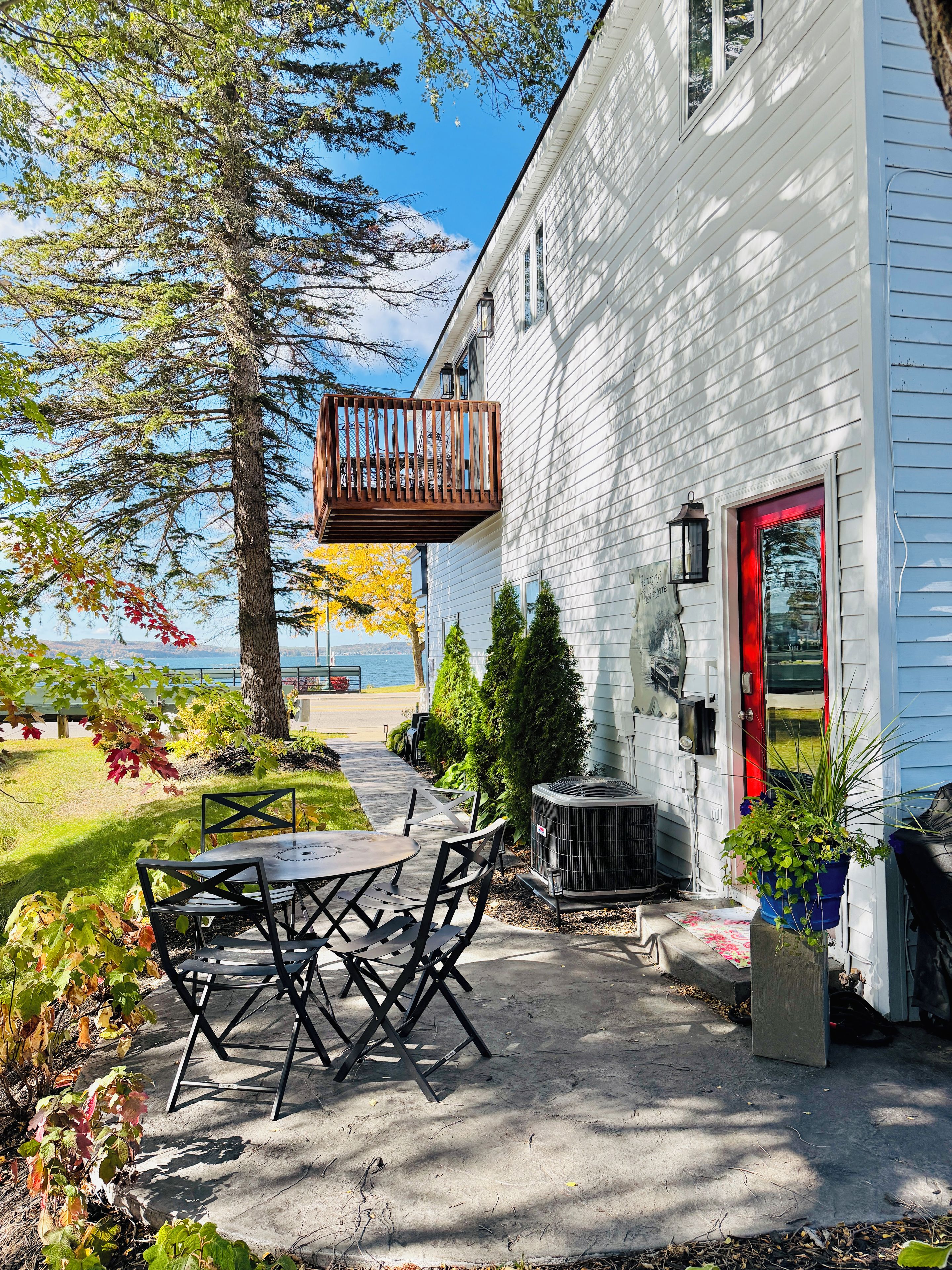 Et hus med terrasse, udendørs møbler og udsigt over vandet.