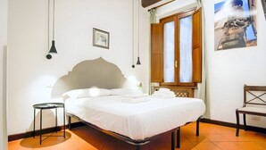 A neatly made bed with white linens, a bedside table, a chair, a window with wooden shutters, and a wall-mounted picture. - Elegantis.it Eat Pray and Love in Rome - Near Navona Square and Campo de' Fiori (Roma)