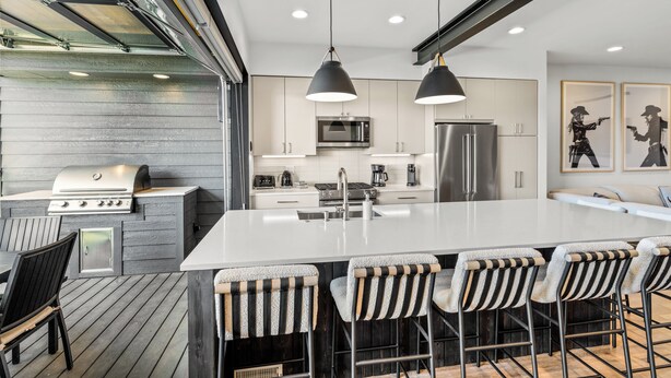 A modern kitchen with a large island, bar stools, and a grill. - Aprés La Joy! AC, Amazing Indoor/Outdoor Kitchen & Deck Space, Private Hot Tub, Amenities! (Steamboat Springs)