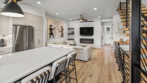 A modern kitchen with a large island, stainless steel appliances, and a dining area with bar stools. - Aprés La Joy! AC, Amazing Indoor/Outdoor Kitchen & Deck Space, Private Hot Tub, Amenities! (Steamboat Springs)