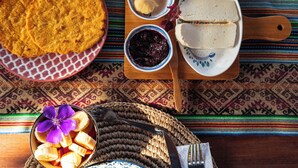 A table with various dishes including bread, a bowl of fruit, and a plate of scrambled eggs. - Tominejo Ecolodge (Neira)