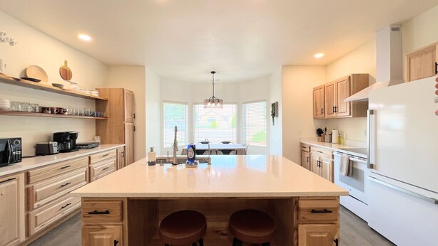 A modern kitchen with a central island, wooden cabinets, and a built-in stove. - Your Kanab Retreat w/ Hot Tub, Game Room, Pet Friendly (Kanab)
