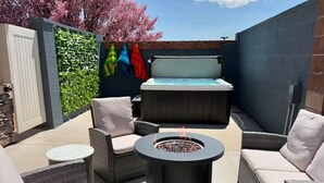 A patio area with wicker furniture, a fire pit, a hot tub, and a green wall with climbing plants. - Your Kanab Retreat w/ Hot Tub, Game Room, Pet Friendly (Kanab)
