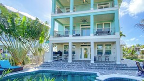 Une maison à deux étages avec une piscine, des balcons et un espace salon extérieur.