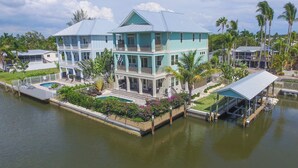 Une grande maison à deux étages, dotée d’un balcon, d’une piscine et d’une jetée qui s’avance dans l’eau.