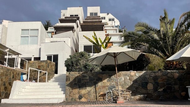 Un hotel moderno con piscina, escalones de piedra y vistas de los edificios circundantes.