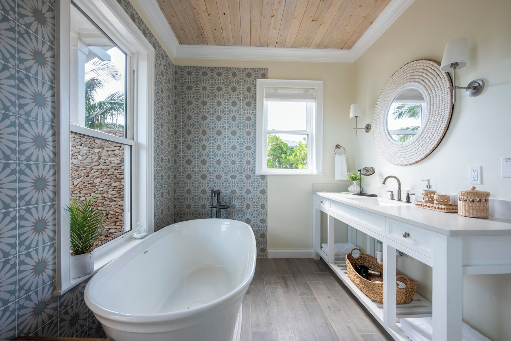 Une salle de bain avec une baignoire sur pieds, un meuble-lavabo blanc avec un miroir et une fenêtre donnant sur un paysage verdoyant.