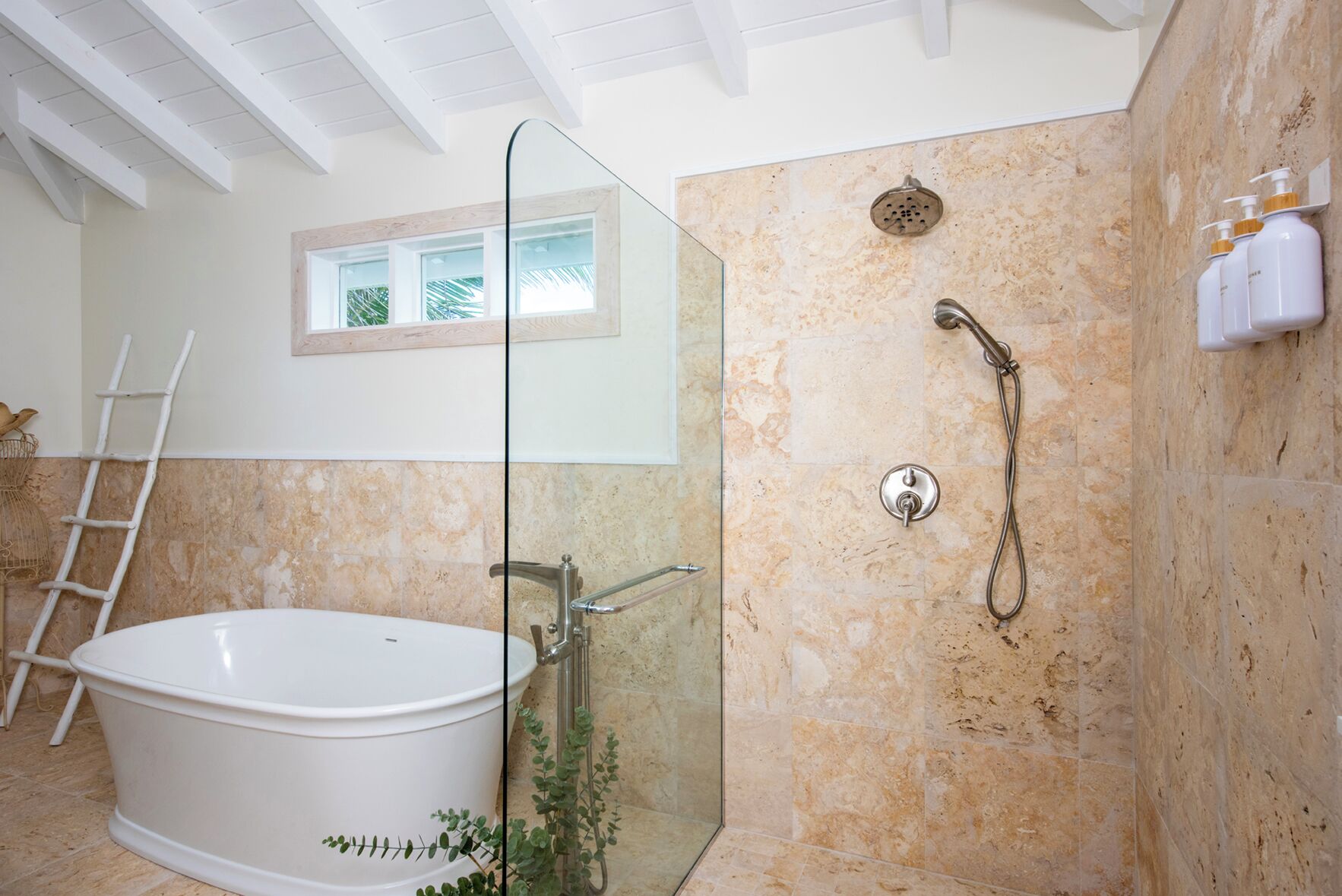 A bathroom with a freestanding bathtub, a glass-enclosed shower, and a window with a view of palm trees.